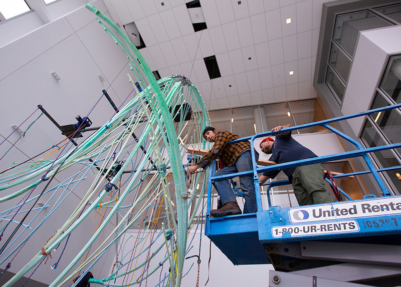 Two men on hydraulic life install sculpture