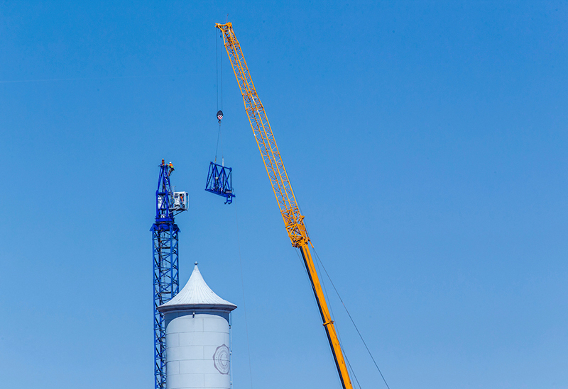 Final arm piece is lifted away from crane tower