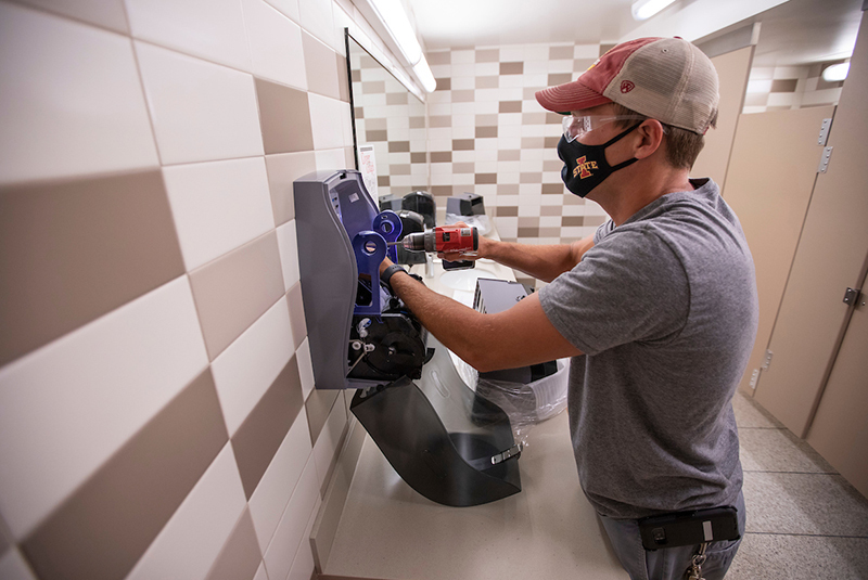 FPM carpenter Justin Abbott drills a new paper towel dispenser i