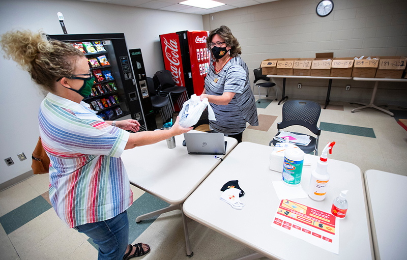 Amy Juhnke (left) receives a package of face coverings from Tami