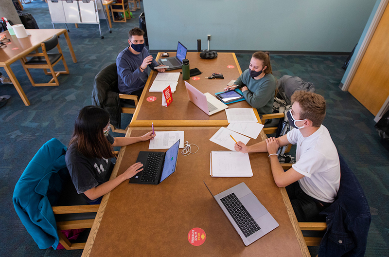 Four students study physically distanced in the libary