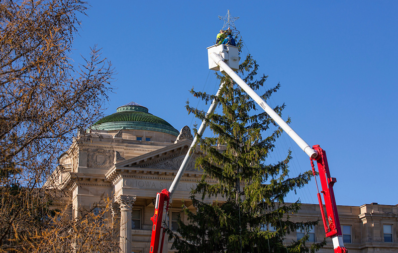 Men in buckets lifts adjust light frame around tree