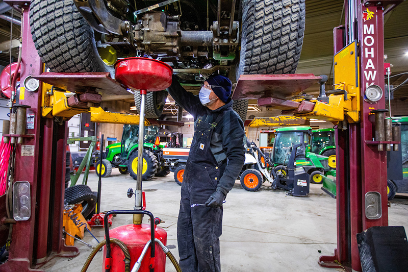Jeff Schreck works on an oil change on a lawnmower tractor