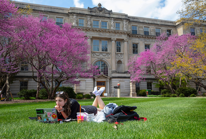 Female student studies on the Marston Hall lawn