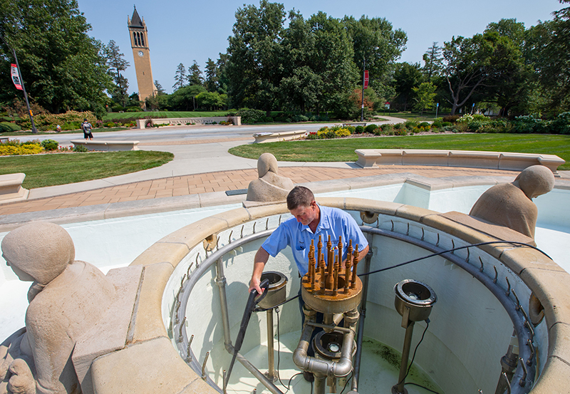 Man uses power washer on outdoor fountain components