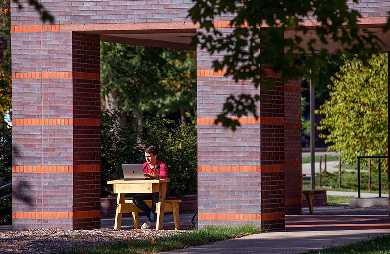 male student works on an outdoor desk