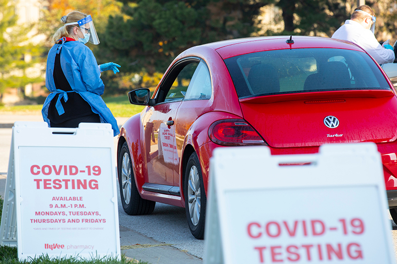 Masked staff administer tests to clients in vehicles