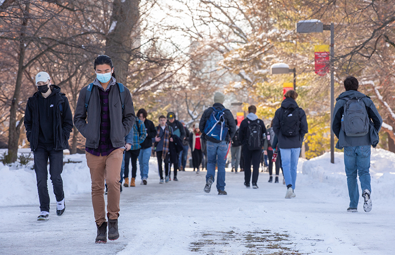 Students walk on snow-lined central campus sidewalk
