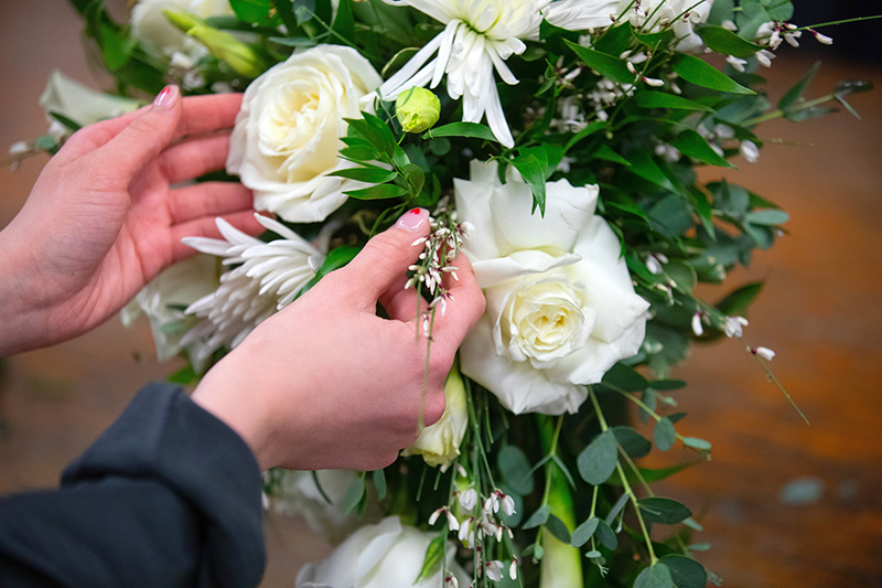 Student hands touch up floral bouquet