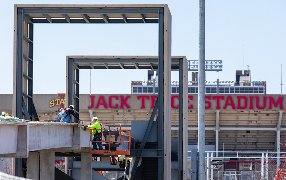 Workers atop pedestrian bridge east of stadium