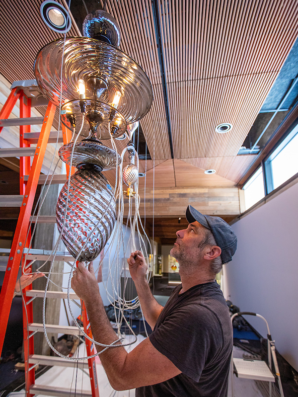 Artist Andy Paiko installs glass chandelier