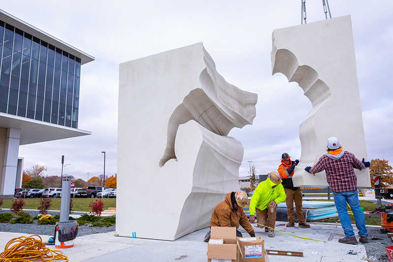 Crew guides large sculpture piece into place