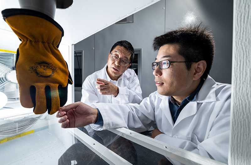 Two researchers observe a work glove in a simulation