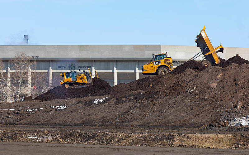 Earth-moving equipment on top of black dirt heap