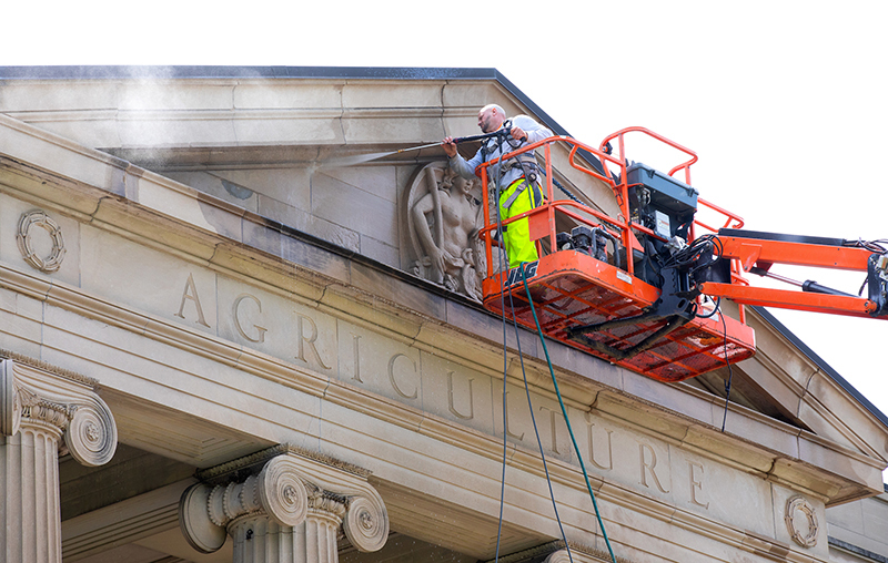 Man power washes front peak of Curtiss Hall