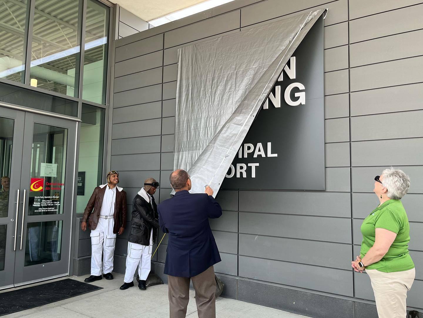 Man removes cover from airport building sign