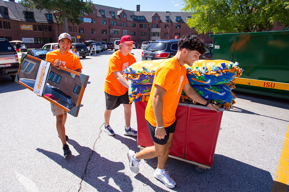 3 student volunteers move items into Helser Hall