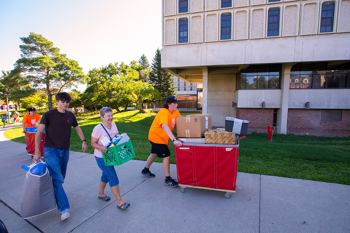 Two student volunteers help family move items to Maple Hall