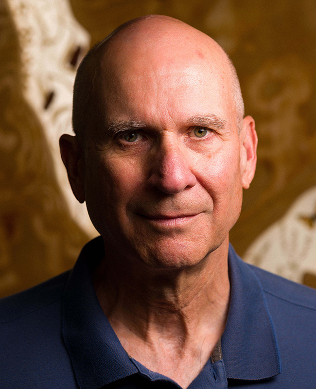 Head shot of white bald man in navy collared shirt