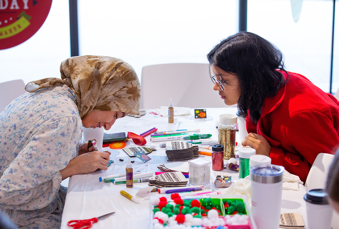 Two international female students decorate 2D tree ornaments at 