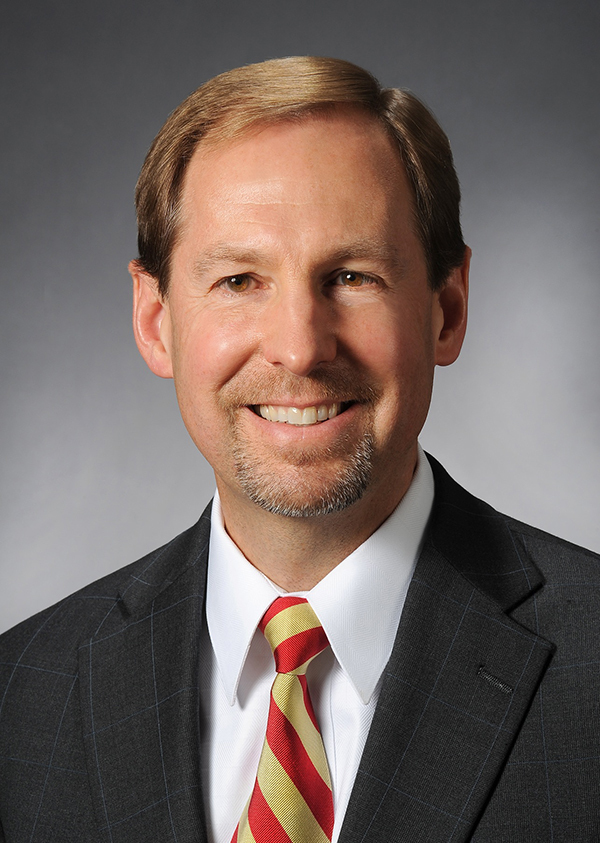 Head shot of man with red/gold striped tie and charcoal suit