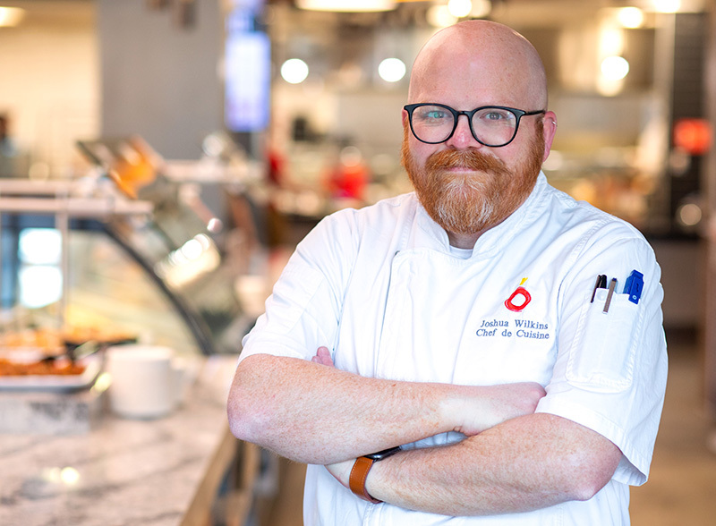 Bearded man wearing glasses in chef's white jacket