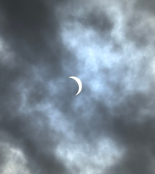 crescent-shaped sun viewed through heavy clouds