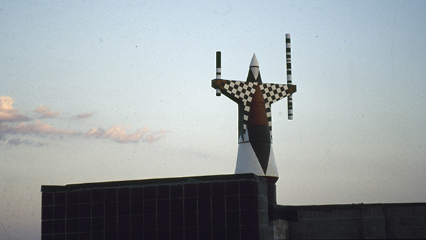 Metal sculpture on building roof at sunset