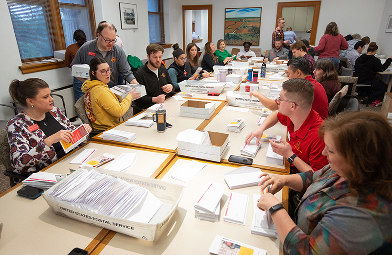 Men and women at conference table put letters in envelopes