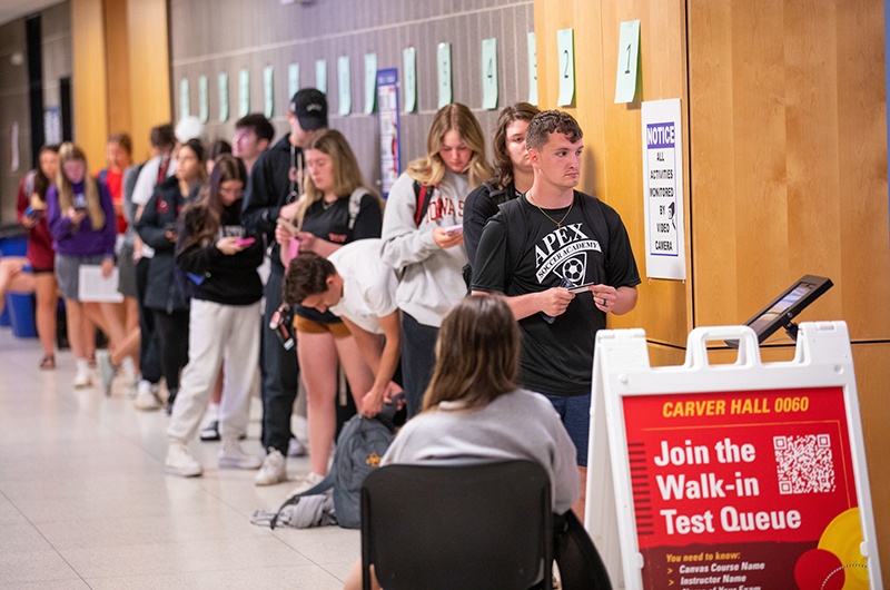 students in line wait to enter test room